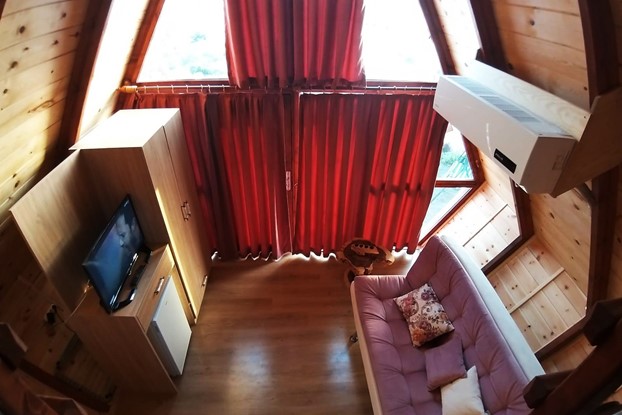 Diamond XL Model Ahşap Bungalov evin asma kattından zemin katının tamamının görüntüsü. Odada üç kişilik bir kanepe, televizyon konsolu ve mini buzdolabı.
