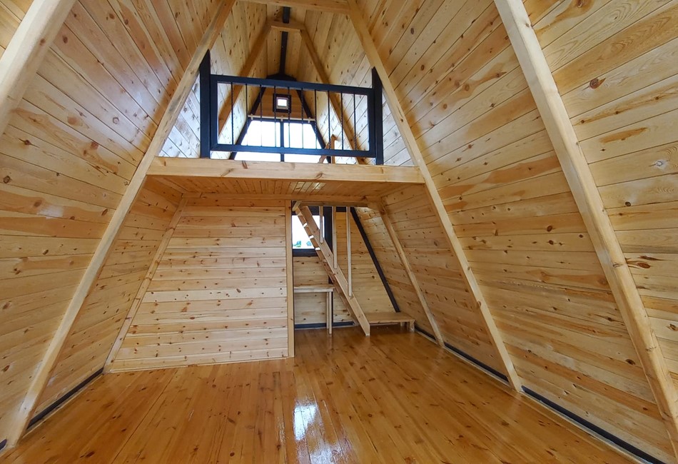 inside of a a-frame cabin  , we can see stairs going to loft and bathroom walls 