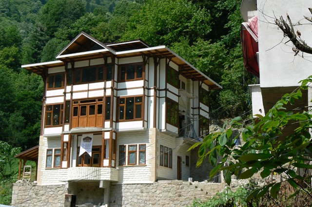 A large mansion in the forest, the ground floor of which is made of stone, the upper two floors of wood and eco panels.